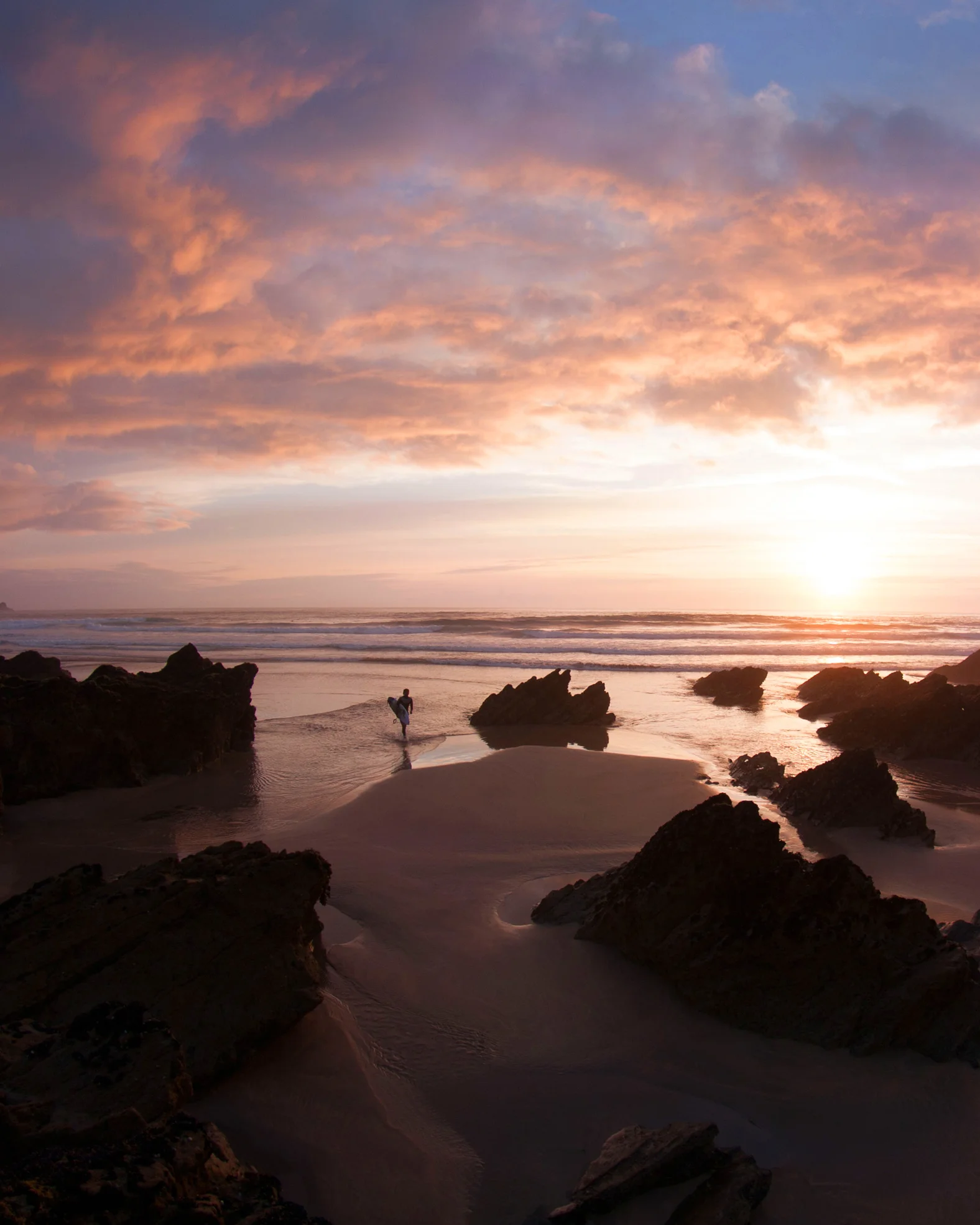 Thumbnail of silhouette of surfer walking back ashore with sunset background